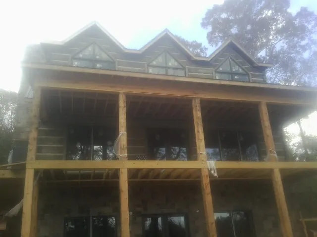 Dormers and porch framing on a large log home under construction — Roof Coating work by our crew in Cedar Springs