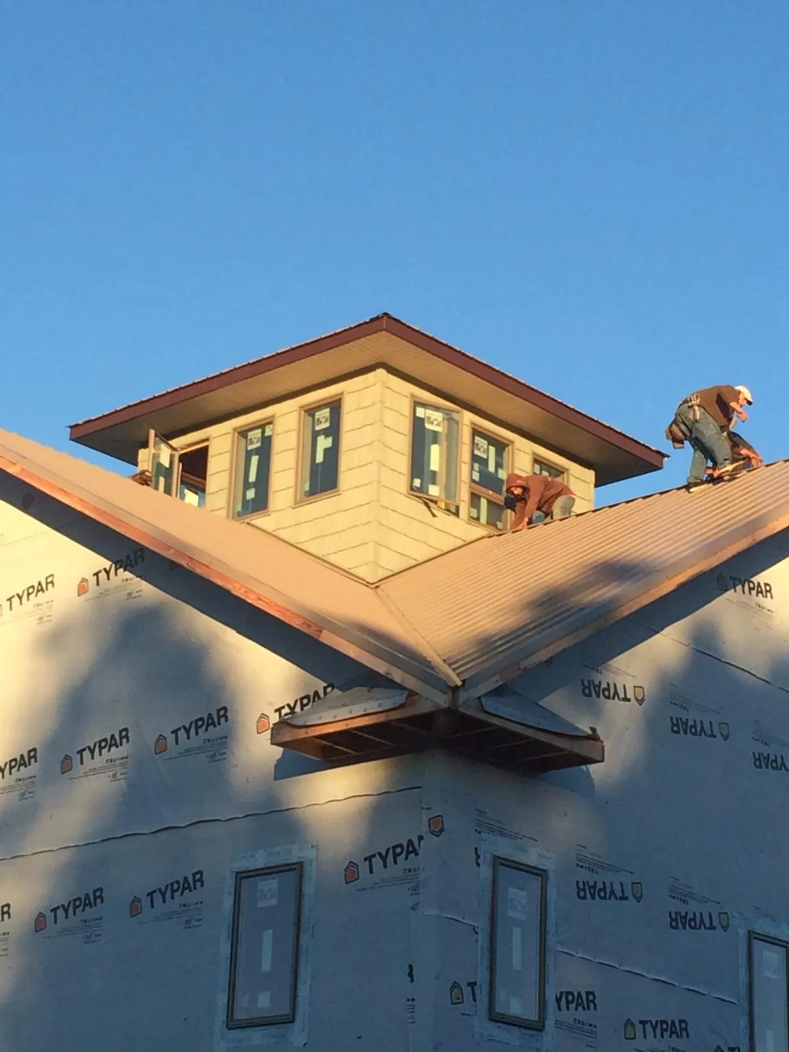 Roofers working around a rooftop cupola on a new metal roof at sunset — Roof Waterproofing in Cedar Springs by Roofing Brothers